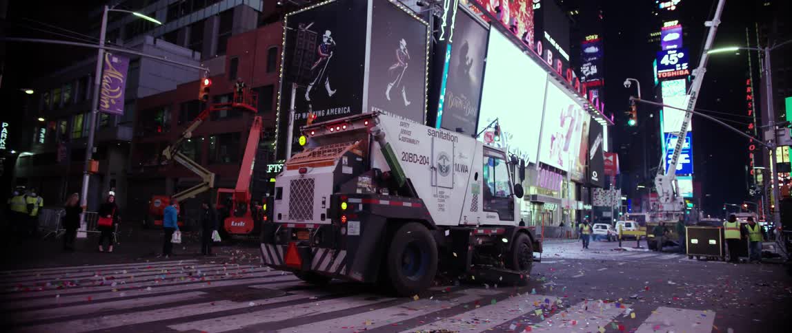 A sanitation vehicle rides forward on a street