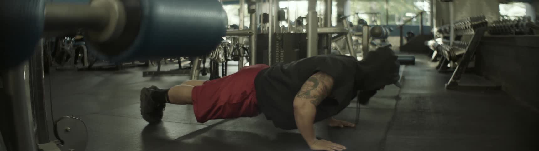 A bearded man does push-ups on the floor of an exercise room