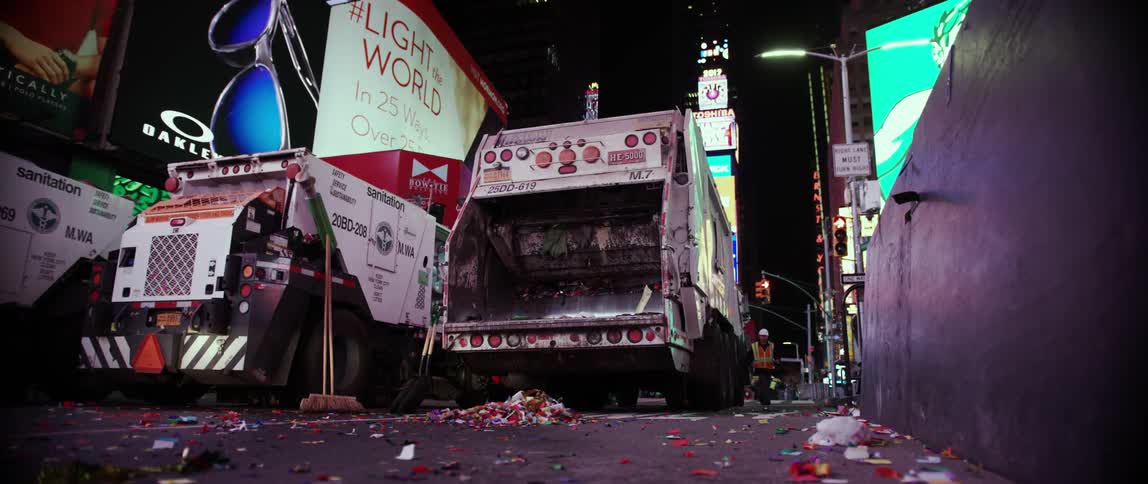 A garbage truck sits next to a street sweeper on this city street