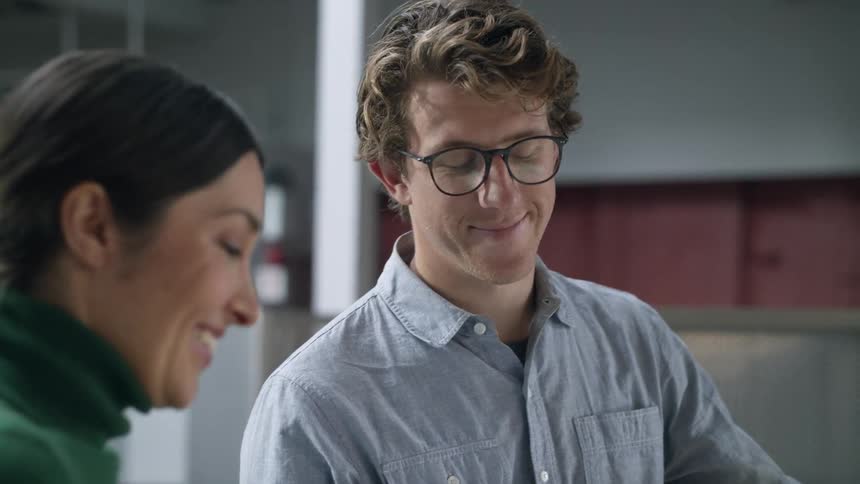 Coworkers stand in office smiling while holding discussion