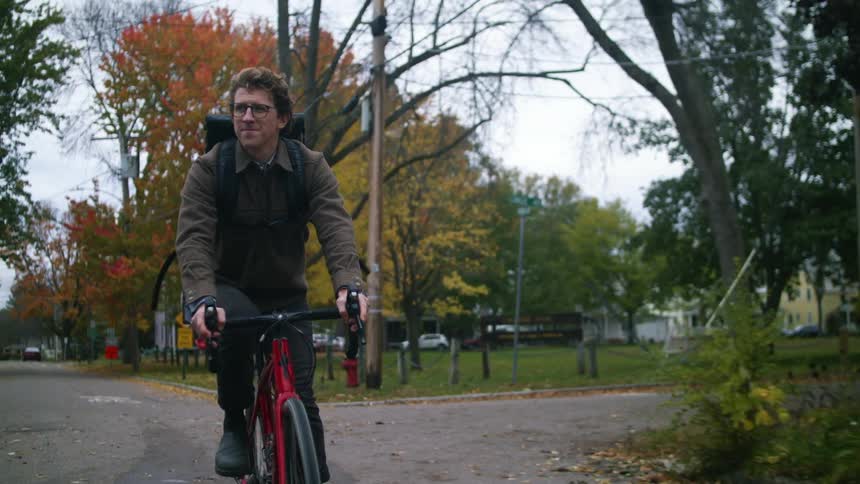 Man driving a red bicycle near a park on the neighborhood