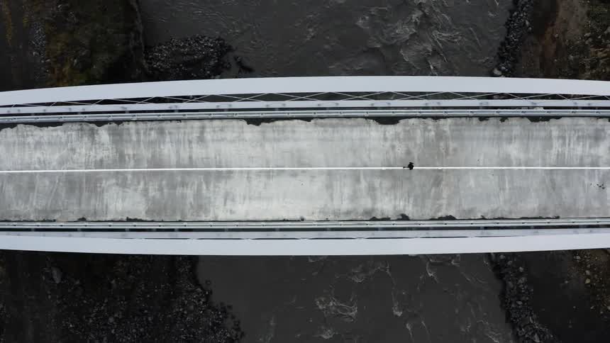 Aerial view of person runs across bridge over river
