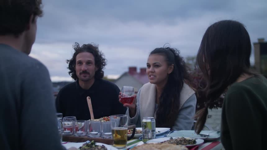 A group of friends drink and eat dinner on a restaurant rooftop