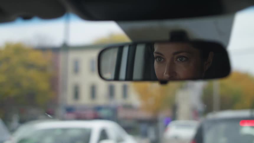 Woman sits in car in traffic near intersection