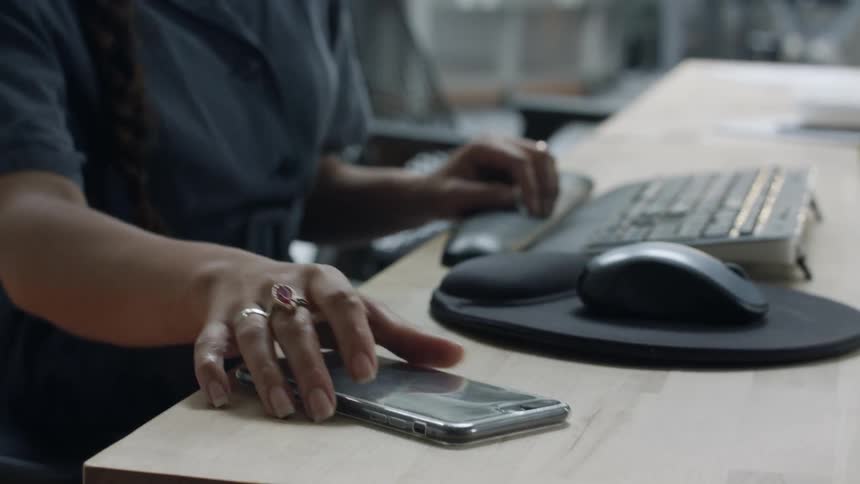 A woman stops working on the computer to answer her phone