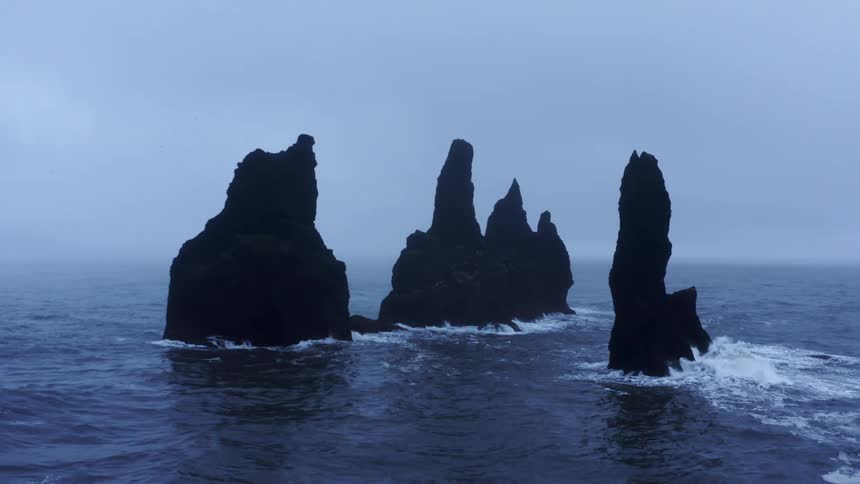 Aerial view of tall rock promontories risingo out of the ocean