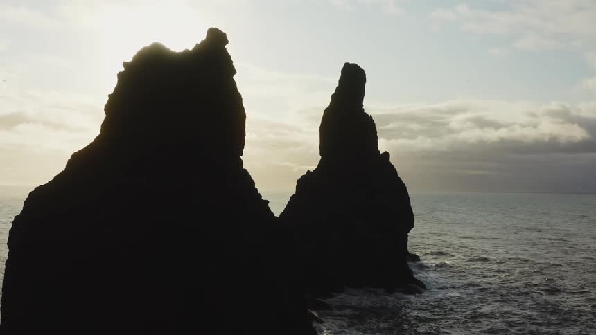 Aerial view of sea stacks being silhouetted against the sun