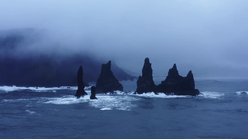 A rocky coast with waves water and fog with the sky and clouds in the background