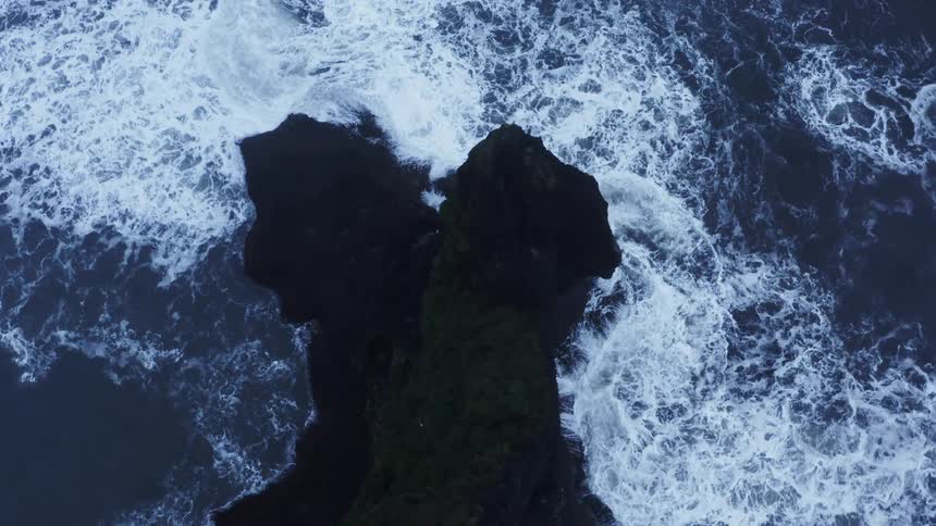 Waves crash onto the shore of a cliff in the ocean