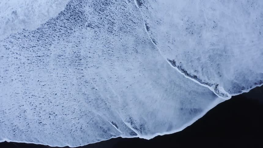 Aerial view of ocean waves breaking against the shore