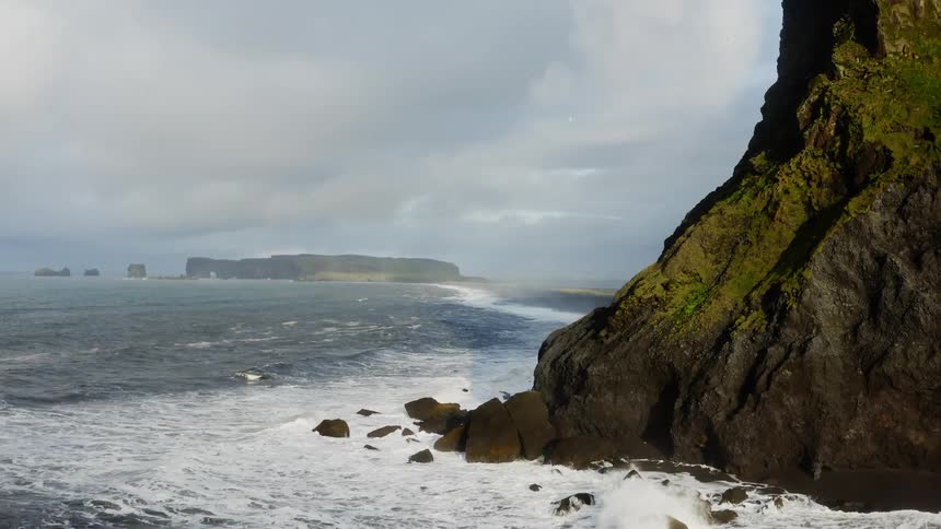 Aerial view of ocean waves crashing on the cliffs in the coast