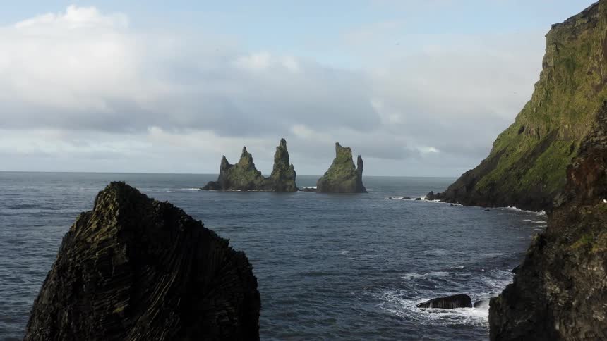 Birds fly over water near promontory cliffs and islets near shore