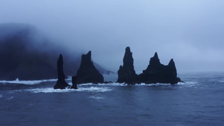 A cliff in the water as waves lap at the edges