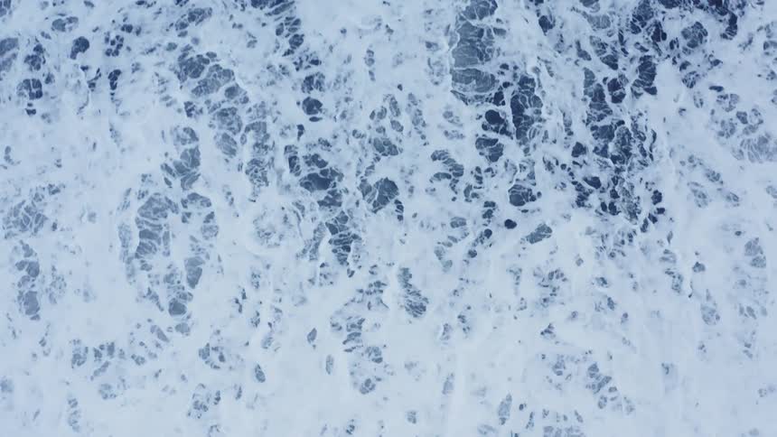 Ocean waves foam as they roll in on the beach