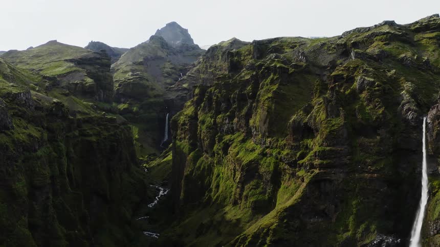 A small waterfall off a cliff connects to a narrow river in a canyon