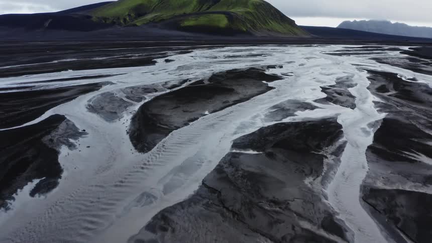 Ice covered rocky terrain with mountains in the distance under a cloudy sky