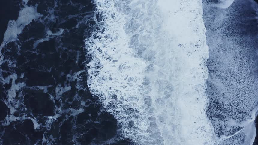 Tall ocean waves rise and fall in heavy wind