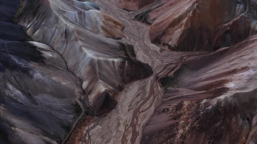 A high altitude aerial view of a mountain range with a dry riverbed in the valley region