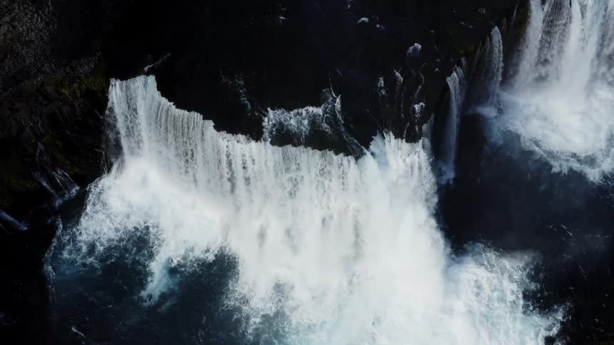 Water rushes down multiple sides of a steep cliff