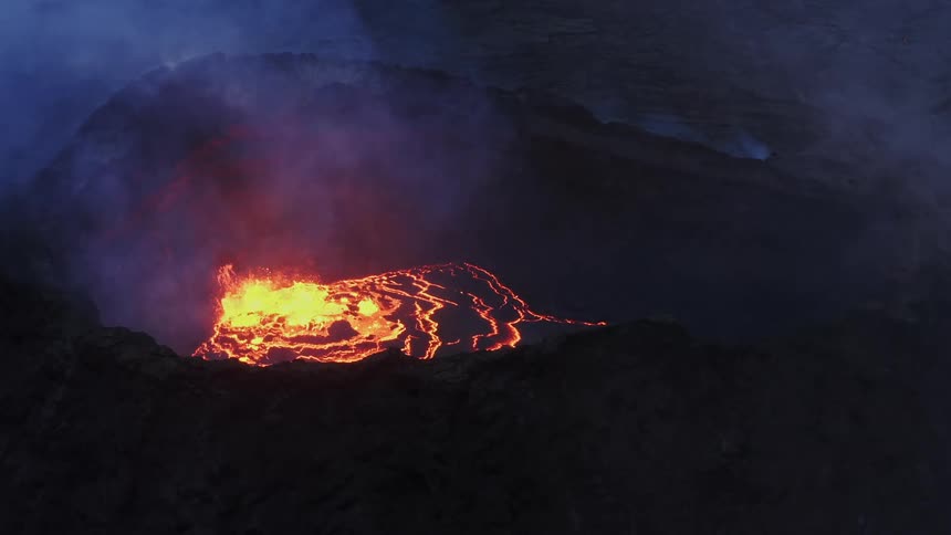 Aerial view of active volcano with a large opening at the top through which gases and lava are forced out