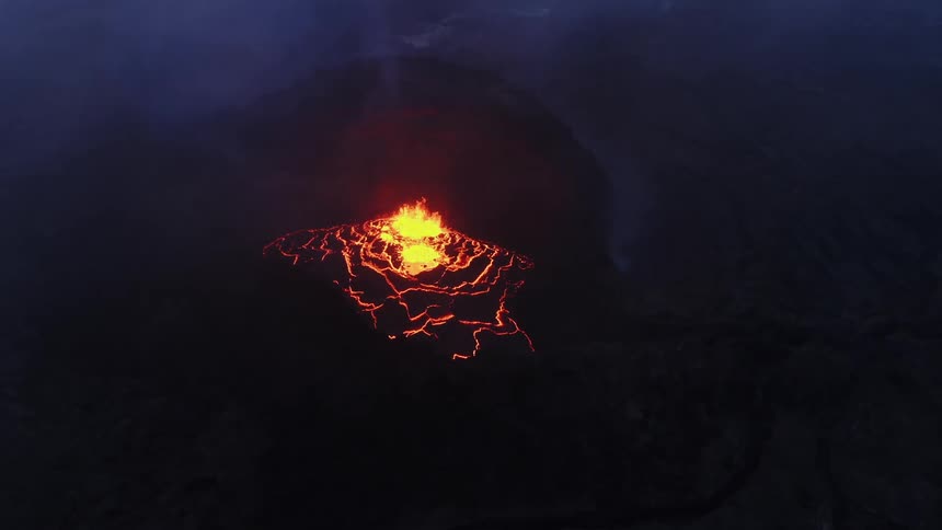 Aerial view of hot magma flowing out of a volcano surrounded by smoke