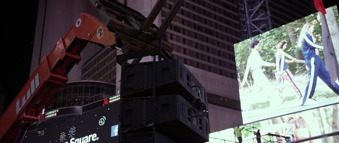 A crane lifts carries some speakers forward