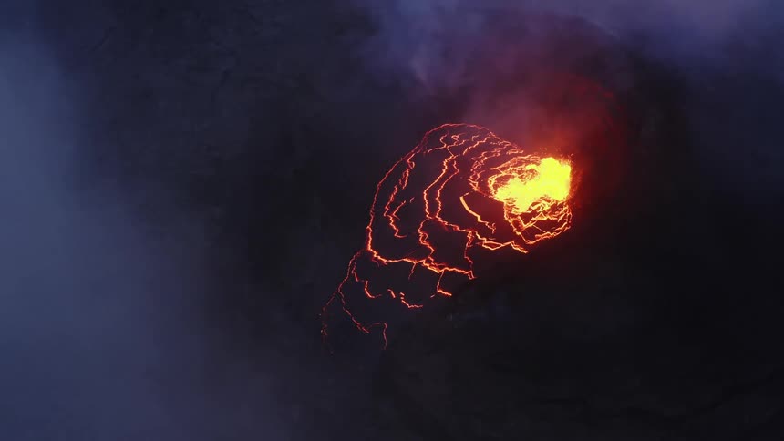 Aerial view of active volcano with a large opening at the top through which gases and lava are forced out