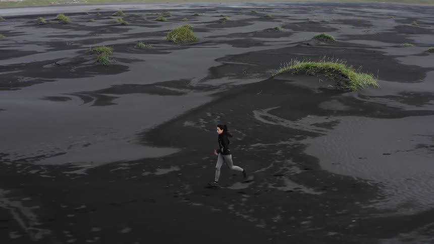 A woman runs across a wet muddy area