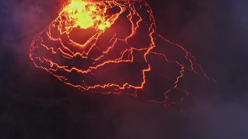 Aerial view of the erupting caldera of a volcano surrounded by smoke