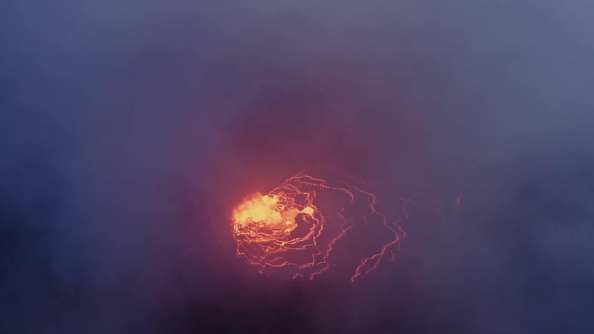 Aerial view of active volcano with a large opening at the top through which gases and lava are forced out