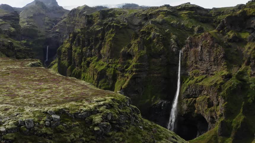 Small waterfalls come down the side of moss covered cliffs