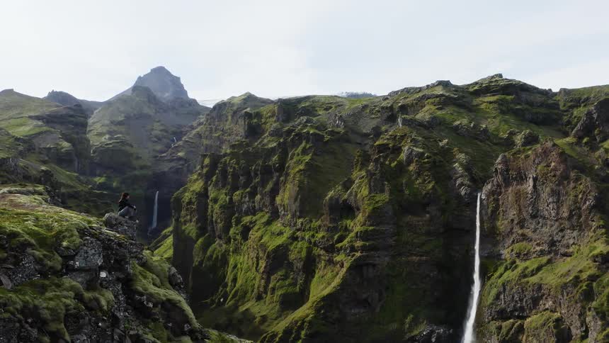 A waterfall rushes from a tall cliff into a narrow river between canyons