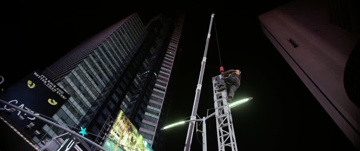 A man is climbing a metal tower near a tall building