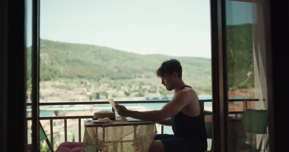 A man and woman sit at a balcony table and the woman throws her hat at the man angrily