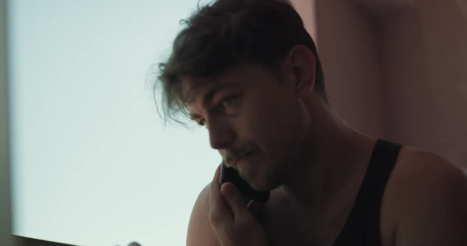 A man talks on his cell phone as he types on his computer