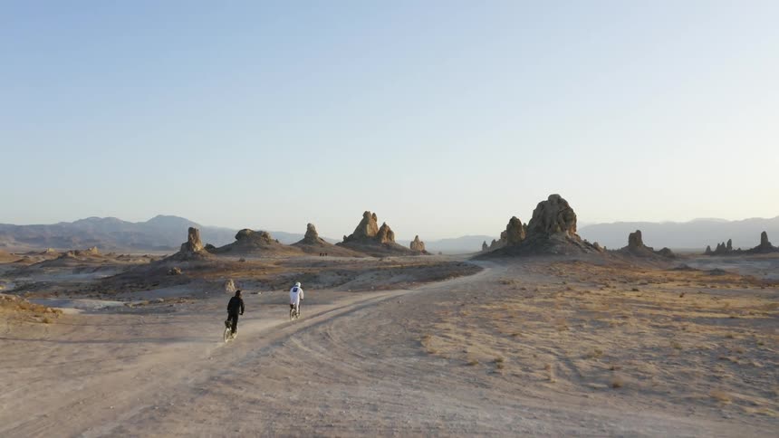 Two people are riding dirt bikes in the desert