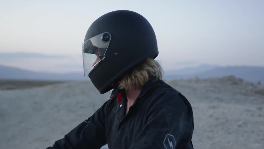 Two riders wearing helmets look out over the landscape