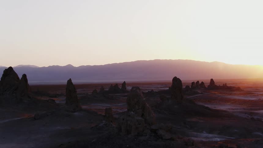 A sand path winds through rock crags in the desert wilderness at sunset