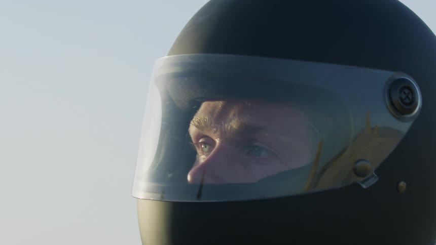 A man putting on a helmet with visor while standing outdoors