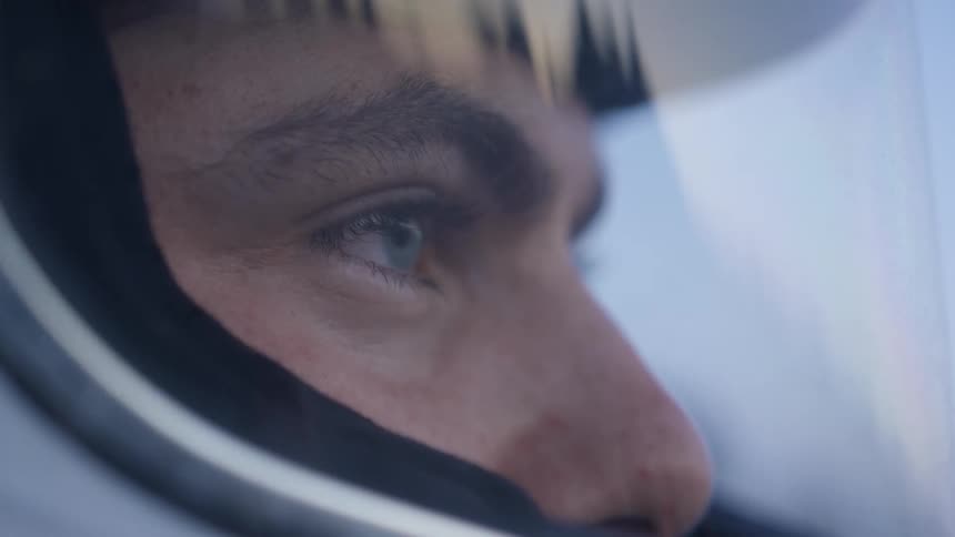 A man wearing a helmet looks out at the landscape which is reflected on his visor