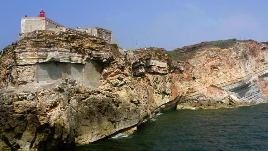 A building is on the peak of a mountain by the shore