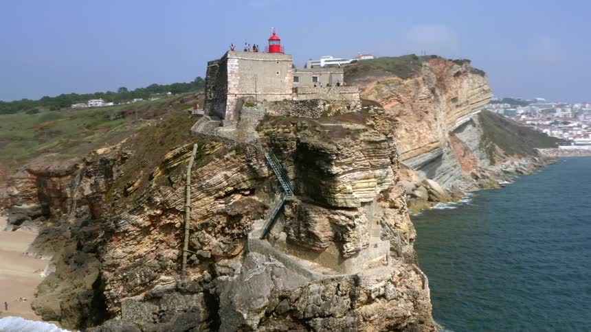 An aerial view of a building perched on a seaside cliff