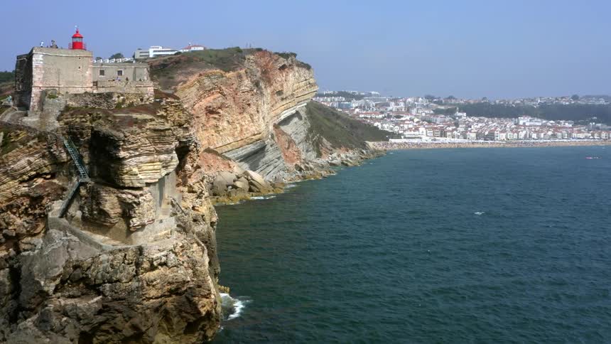 A castle sits on a cliff overlooking the ocean