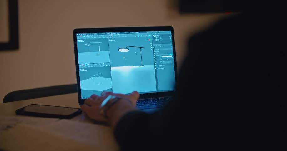 A lamp and schematics are displayed on a laptop screen as a man works to animate the design