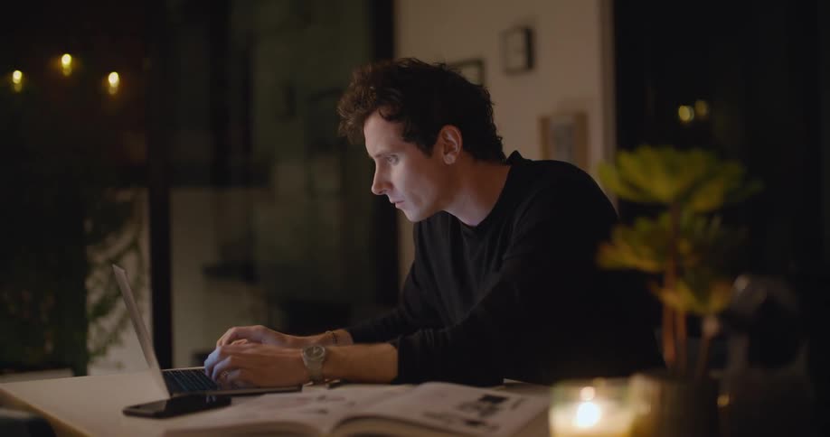 A man sitting in a room using a laptop at night