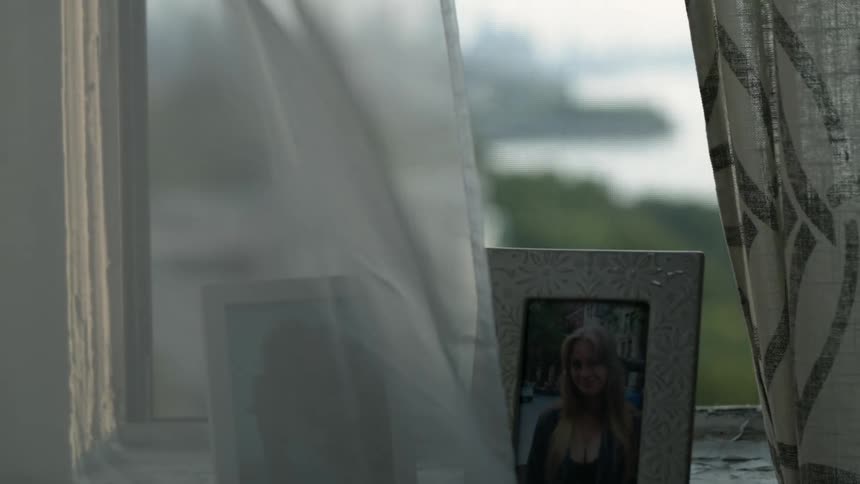 City skyline seen from apartment window with photo frames on the sill