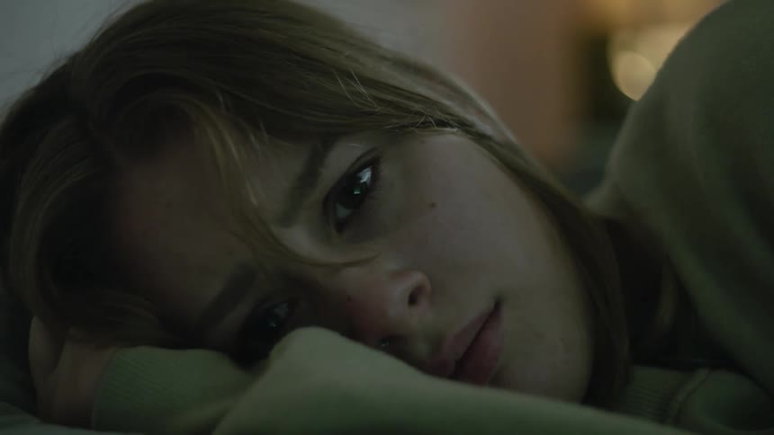 Crying woman lying on her side wipes her tears with sleeve