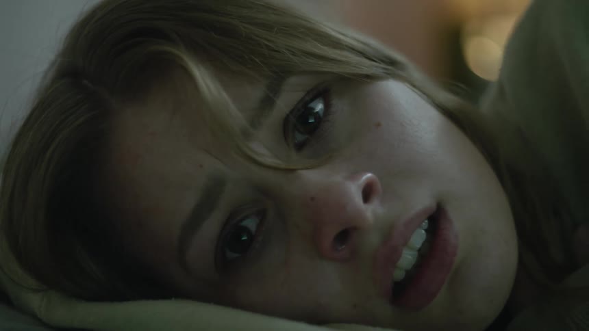 Close up of the face of a sad crying young woman laying in bed