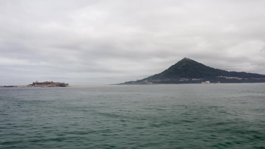 The ocean with water with land the sky and clouds in the background