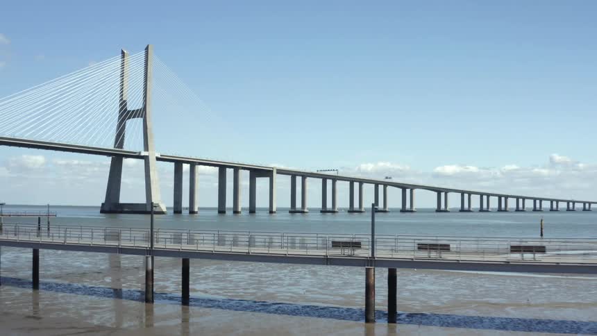 A cable suspension bridge expands out into ocean waters on sunny day